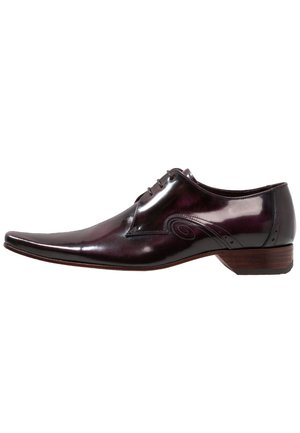 Zapato de vestir para hombre en color burdeos oscuro brillante, con puntera puntiaguda, cordones delanteros, costuras decorativas y tacón bajo de madera, vista lateral.