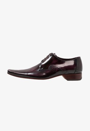 Zapato de vestir para hombre en color burdeos oscuro brillante, con puntera puntiaguda, cordones delanteros, costuras decorativas y tacón bajo de madera, vista lateral.