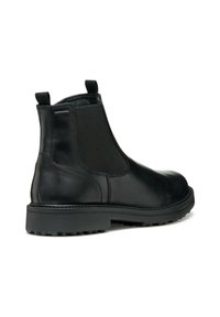 Bottine Chelsea en cuir noir avec des panneaux latéraux élastiques, une languette et une semelle en caoutchouc robuste avec des détails de traction. Fini lisse.