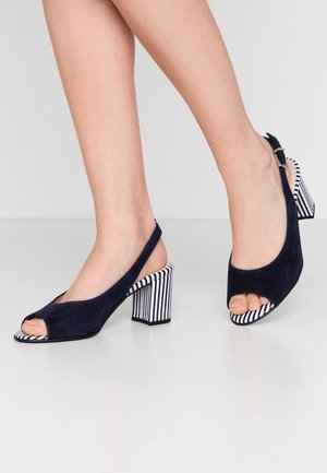 Navy Wildleder Slingback-Absätze mit offenem Zehenbereich, ausgestattet mit einem gestreiften Blockabsatz und einer weißen gestreiften Innensohle. Verstellbarer Knöchelriemen ist enthalten.