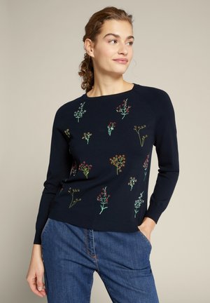 Granatowy sweter z dzianiny z haftem w kwiaty w odcieniach czerwieni, żółci i zieleni. Okrągły dekolt i długie rękawy z dopasowaną sylwetką.