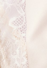 Pizzo avorio con motivi floreali intricati accanto a un tessuto satinato liscio, entrambi in tonalità neutre, creando un contrasto di textures.
