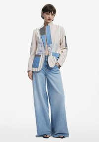 Patchwork blazer with blue, white, and gray fabrics; features a fitted collar, oversized fit, and wide-leg light denim pants.