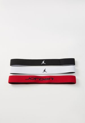 Tre fasce elastiche per sport: nera con logo bianco, bianca con logo nero e rossa con testo nero, tutte con una finitura testurizzata.