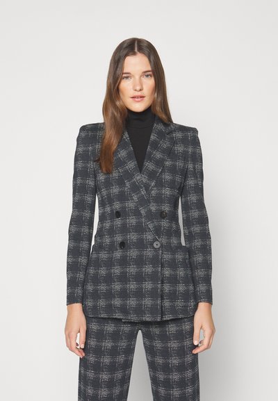 Dobbeltradet blazer i et mørkt ternet mønster med en struktureret pasform, lavet af et tekstureret stof. Sorte knapper og revers fremhæver designet.