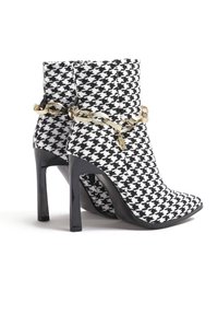 Černobílé šaty houndstooth na kotníkové boty se špičatou špičkou, stiletto podpatkem a zlatým řetízkem kolem kotníku.