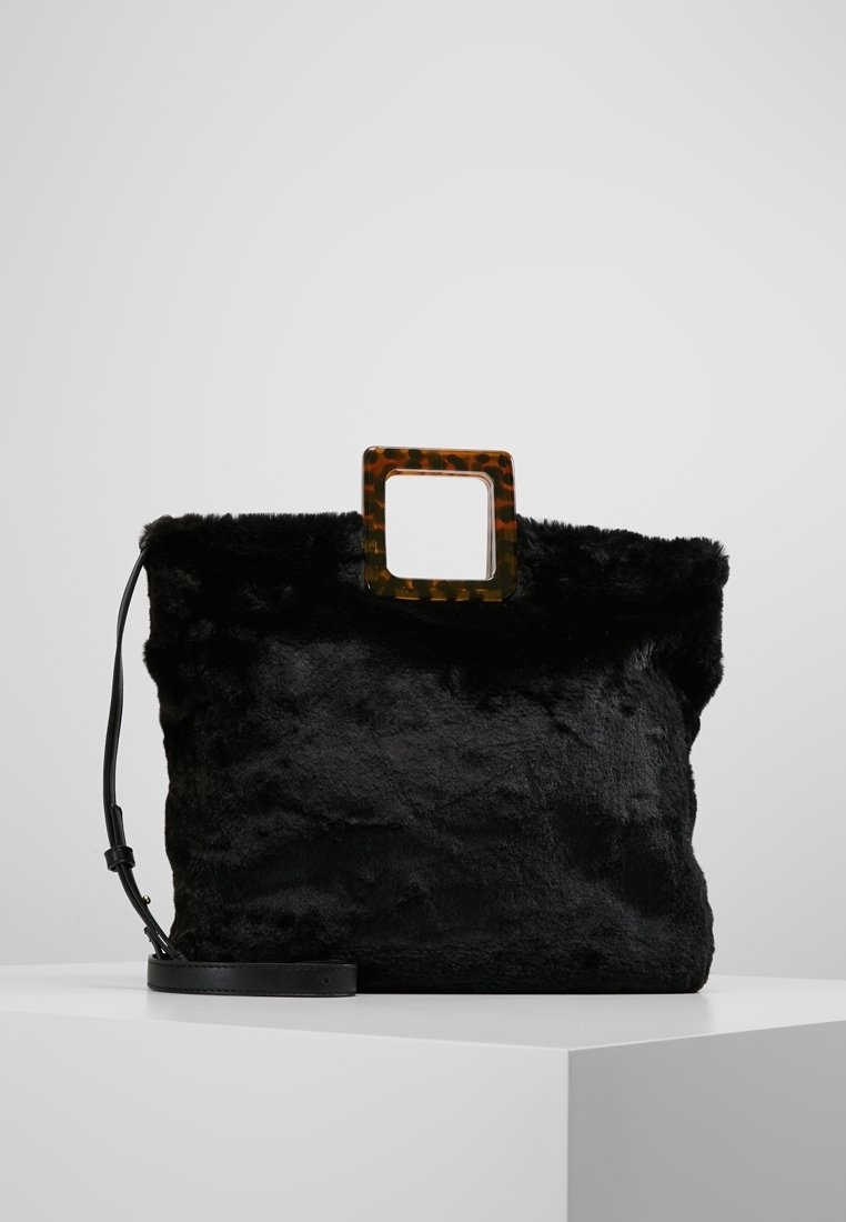 Svart faux fur-handväska med en texturerad yta, fyrkantigt sköldpaddsblockhandtag och en justerbar svart axelrem för mångsidiga bäralternativ.