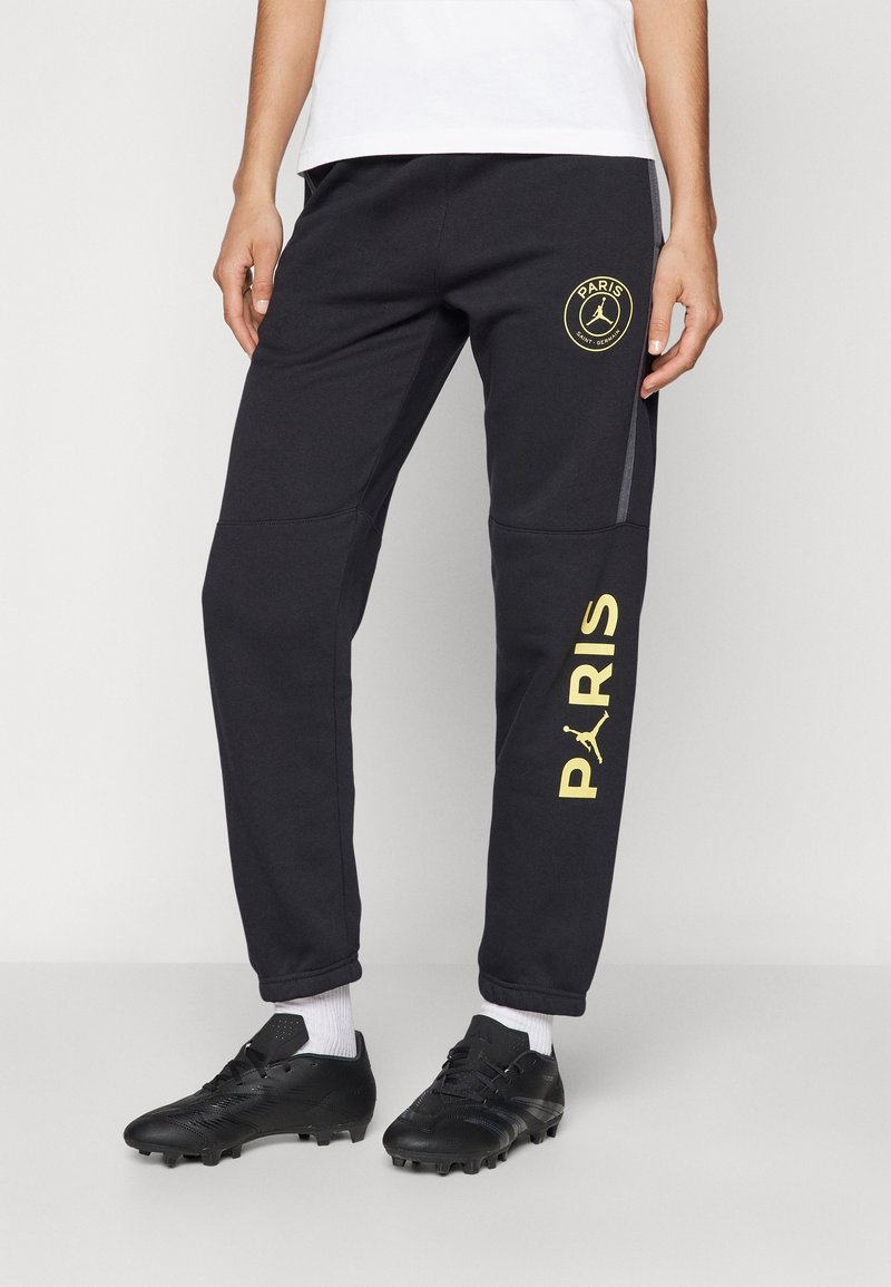 Czarne spodnie dresowe z złotym logo Paris Saint-Germain, o dopasowanym kroju, wykonane z teksturowanej tkaniny, z dodatkowym graficznym akcentem po bokach.