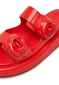 Red sandal with dual rose embellishments, smooth leather material, wide strap, and a thick platform sole. Flat base for stability.