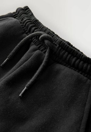 Svarta fleece-joggingbyxor med elastisk midja, dragsko och metallspetsar, som visar en mjuk textur och sömmar.