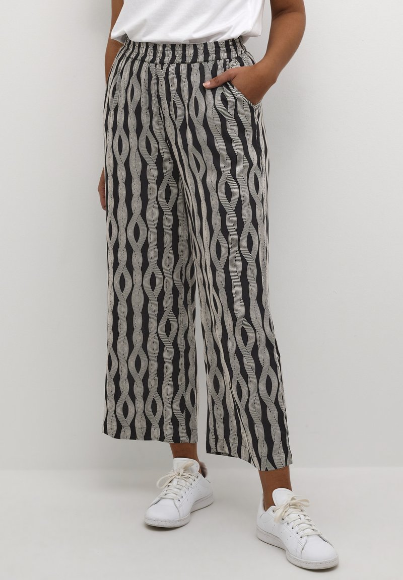 Pantalons évasés en tissu léger, présentant un motif ondulé noir et blanc, une taille élastique et des poches latérales.