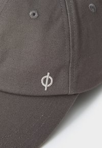 Gray cap made of cotton, featuring a textured surface and a white embroidered logo on the side. Adjustable strap not visible.