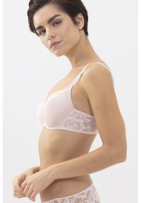 Vaaleanpunainen rintaliivi, jossa on sileä, puolimatta etuosa ja pitsikoristelu sivuilla. Säädettävät olkaimet ja kukkakuvioinen pitsi lisäävät tekstuuria.