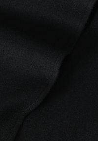 Tissu en feutre noir, doux au toucher, avec une texture lisse, présentant des plis subtils et une couleur uniforme. Aucun motif visible ni détail de quincaillerie.