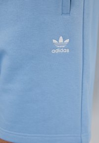 Adidas blå bomullsshorts med en brodert hvit logo på venstre side, med en glatt tekstur og standard passform.