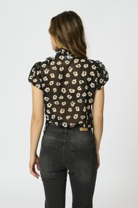 Blusa nera a fiori con maniche a sbuffo e scollatura arricciata, abbinata a jeans grigi scuri con retro semplice e due tasche.