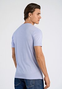 Vaaleanlavententupuolisleeve-t-paita, jossa on pyöreä kaula-aukko, sileä pinta ja rento istuvuus, yhdistettynä tummiin farkkuihin.