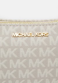 Beige kangaskukkaro, jossa on hienovarainen MK-kuvio ja kultainen "MICHAEL KORS" -logo. Sisältää vetoketjun kultaketjulla.