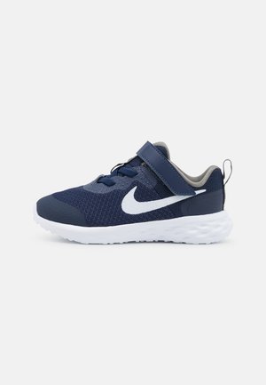Ténis de desporto azul-marinho com parte superior em malha, detalhes brancos, atacadores elásticos e uma fita de Velcro. Projetados para conforto e flexibilidade.