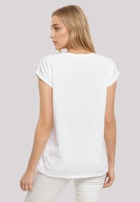 White, short-sleeve t-shirt with rolled sleeves and a relaxed fit. Soft cotton material, curved hemline, and a plain back design.