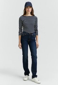 Tumesinise ja valge triibuline pikakäise särk, mida kannavad tumedate siniste teksadega. Modellil on peas tumesinine müts ja jalas valged tossud.