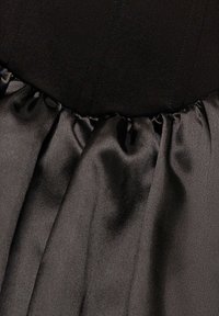 Zwarte jurk met een getailleerd bovenstuk met verticale naden en een geplooide satijnen rok, met een gladde textuur en subtiele glans.