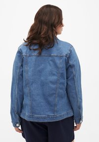 Sinine teksajakk klassikalise disainiga, millel on nööbiga mansetid, sirge lõige ja kootud tekstuur. Tagantvaates on nähtavad õmbluse detailid.