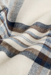 Karierter Stoff in Blau-, Braun- und Cremefarben mit weicher Textur und diagonalen Linien, die ein kariertes Muster bilden.