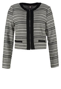 Veste courte noir et blanc avec motifs géométriques, dotée d'un col rond, de manches longues et d'une fermeture éclair frontale. Deux poches latérales.