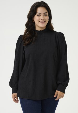Sort tekstureret bluse med høj hals, puflange ærmer og indsamlede manchetter. Blødt materiale med subtile mønsterdetaljer.