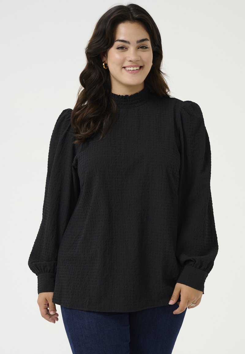 Zwarte textuurblouse met een hoge hals, volumineuze lange mouwen en gathered manchetten. Zacht materiaal met subtiele patroondetails.
