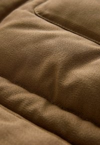 Kareda, pruun kangas, millel on kudumise muster, millel on lisatud mõõtmete ja pehme, patjadega välimuse saavutamiseks õmmeldud osad.