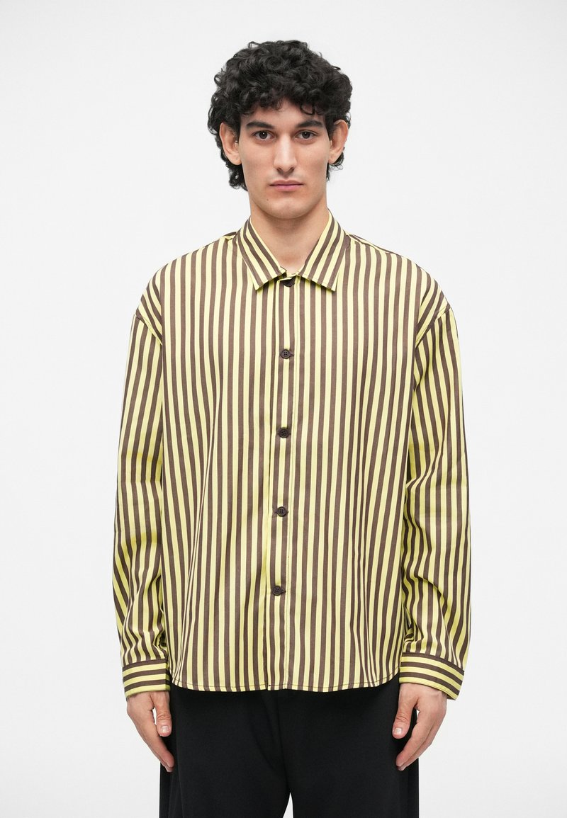 Striped button-up shirt with yellow and brown stripes, featuring a collar and long sleeves. Smooth texture with a relaxed fit.