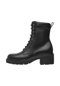 Bottine en cuir noir avec un laçage sur le devant, œillets en argent, bout rond et talon épais. Embellie d'une languette à l'arrière.
