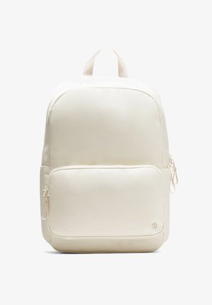 Cremefarvet rygsæk med glat stof, rund form, to lynlåslommer og et håndtag på toppen til bæring. Minimalistisk design.