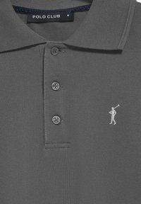 Grå polotröja med strukturerad yta, tre knappar och en liten broderad vit figur-logotyp på vänster bröst. Märkesetikett: Polo Club.