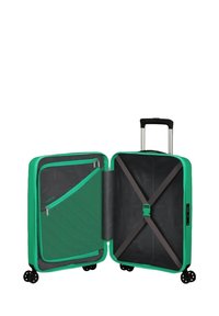 Valigia rigida verde con interno in tessuto nero, dotata di una tasca con zip, cinghie regolabili e quattro ruote per la mobilità.