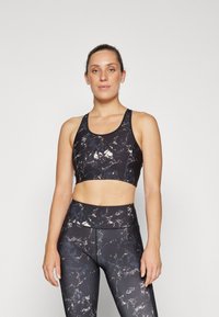 Svart sports-bh og høyt liv leggings i et marmorert mønster med nyanser av svart, hvitt og grått. Glatt, elastisk stoff.
