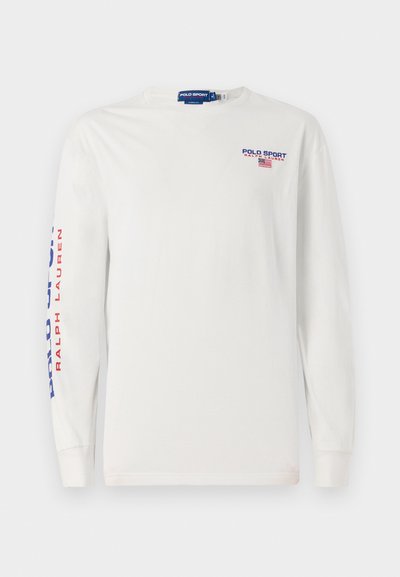 T-shirt de manga longa branca feita de algodão. Apresenta "POLO SPORT" em texto azul e vermelho no braço esquerdo e no peito. Gola redonda simples.