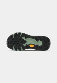 Rubberen buitenzool met een zwart, gestructureerd patroon en lichtgroene accenten. Heeft een oranje Vibram-logo en robuuste profielzolen voor grip.