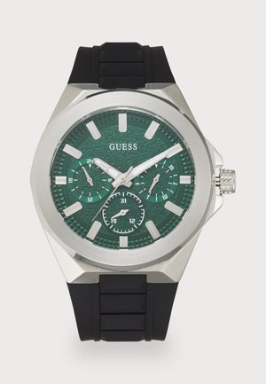 Montre avec bracelet en caoutchouc noir, cadran texturé vert, boîtier en acier inoxydable, marqueurs d'heure luminescents et accents argentés. Sous-cadrans pour un chronométrage précis.