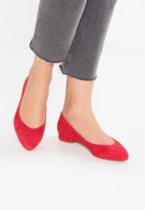 Røde ballerinasko i ruskind med rund tå og lav hæl, kombineret med grå cropped jeans med frynset kant.