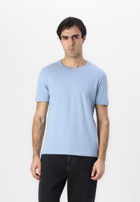 Camiseta de manga corta de color azul claro, hecha de algodón, con un diseño de cuello redondo. Textura lisa, forma ajustada y construcción simple sin patrones.