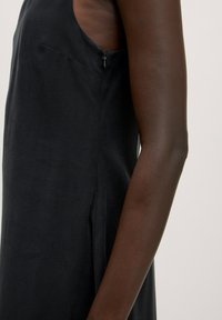 Schwarzes ärmelloses Kleid mit einem seitlichen Reißverschluss, das über eine glatte Textur und einen runden Ausschnitt verfügt. Minimalistisches Design mit einer figurbetonten Silhouette.
