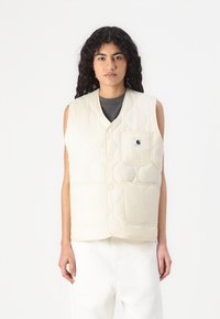 Quiltet, ermeløs vest i kremfarget stoff med V-hals, frontknapper og to lommeposter; har et lite merke-logo-patch.