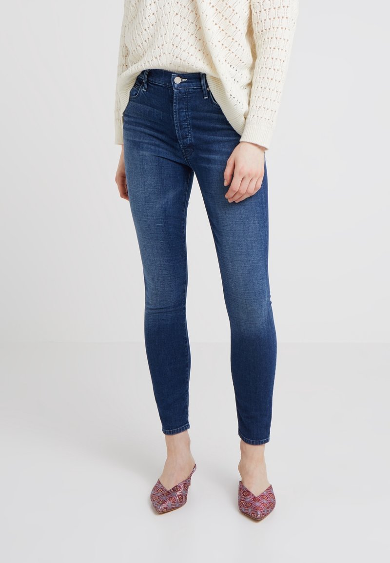 Úzké džíny v tmavě modré barvě, s klasickým pětikapsovým designem, zapínáním na knoflík a jemným žmolkováním vpředu.