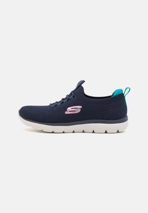 Zapatilla deportiva de malla azul marino con superficie texturizada, mediasuela blanca y detalles en turquesa, con un logotipo rosa en el lateral.