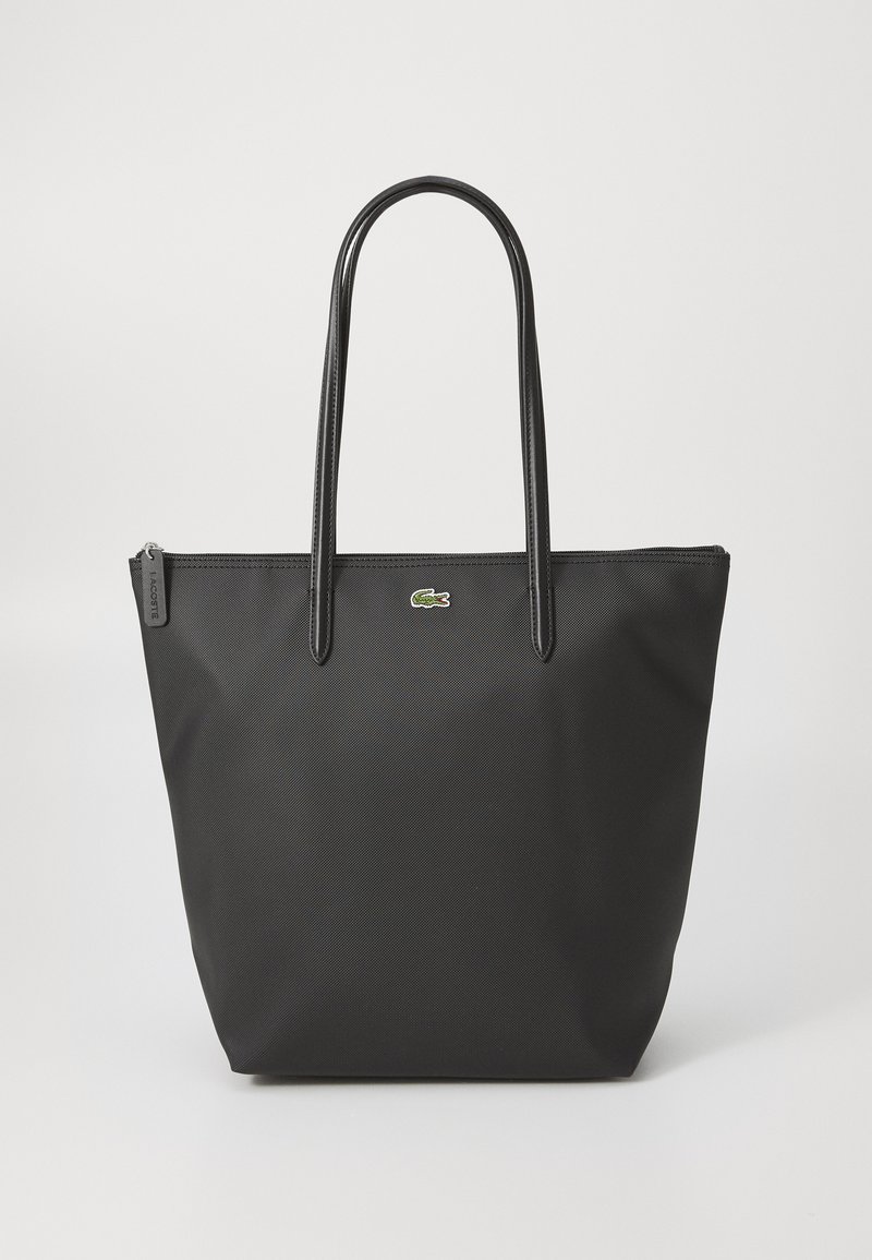 Geantă tote neagră cu exterior neted, mânere lungi și închidere cu fermoar. Prezintă un mic logo de crocodil verde pe partea din față.
