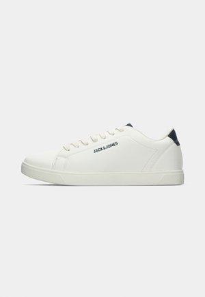 White sneakers with a smooth leather-like upper, round toe, and textured rubber sole. Features navy accents and side logo text.