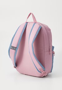 Mochila de tela rosa con detalles azules, de forma rectangular, con correas ajustables, un asa en la parte superior y un bolsillo con cremallera lateral.